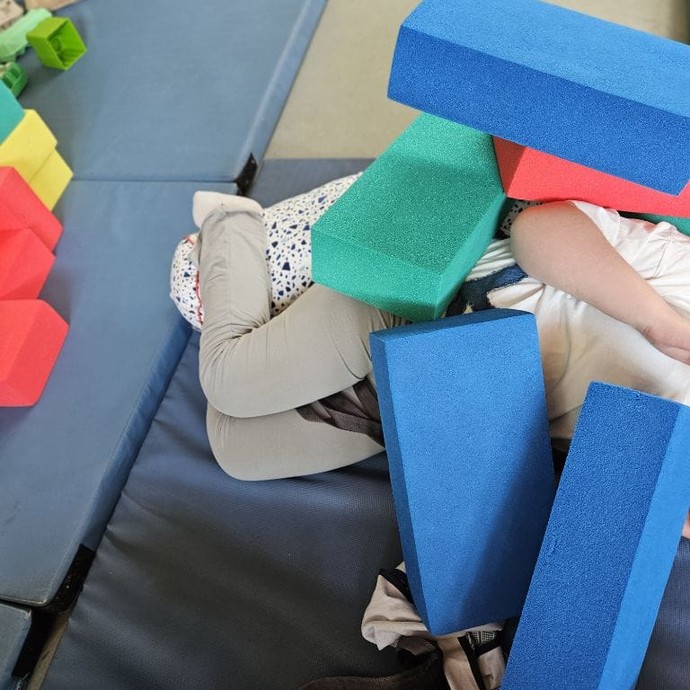Schüler versteckt sich unter Bausteinen (vergrößerte Bildansicht wird geöffnet)