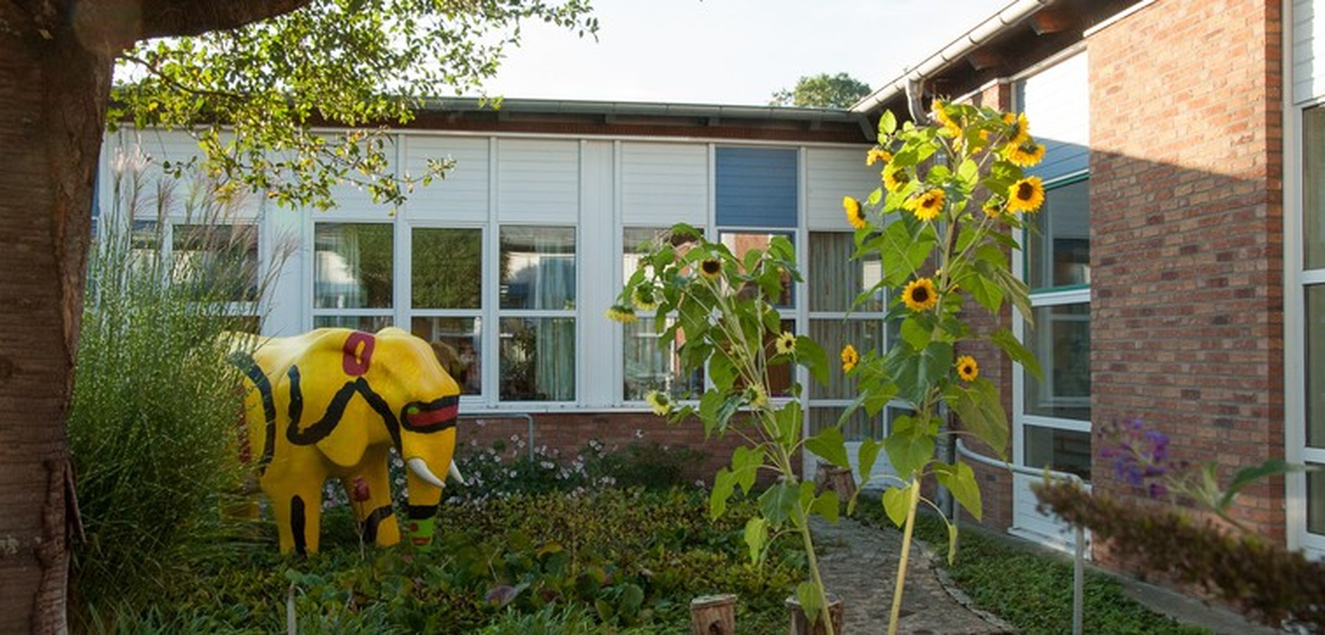 Garten im Innenhof der Schule mit Sonnenblumen unf Kunstobjekten.