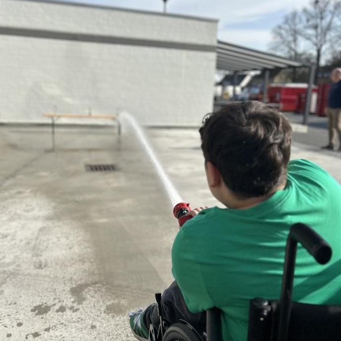 Schüler mit Wasserschlauch (vergrößerte Bildansicht wird geöffnet)