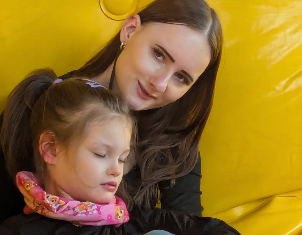 Eine junge Frau mit Schülerin auf dem Schoß